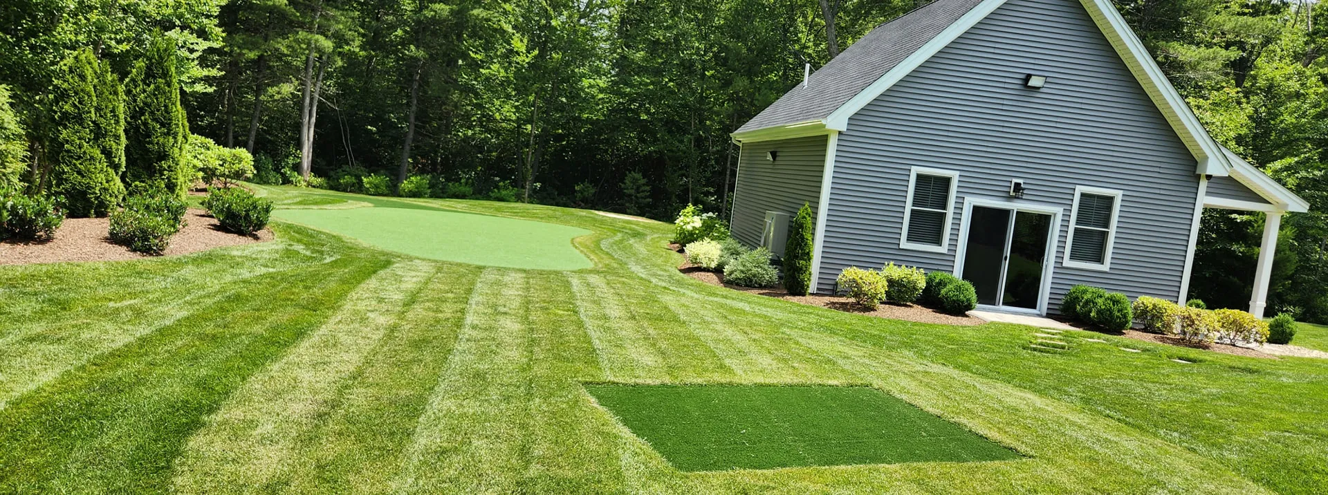 Backyard lawn with putting green beside a guest house